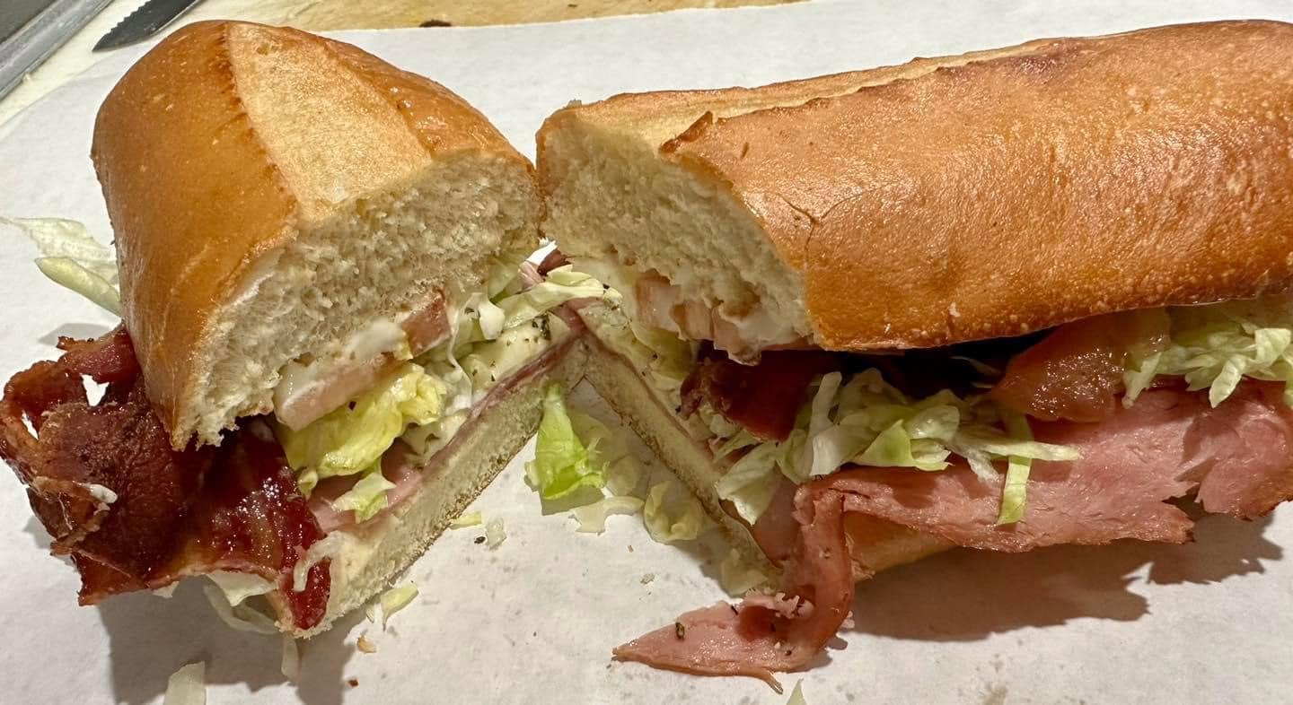 Hot oven grinder cut open with bacon, ham, lettuce and tomato